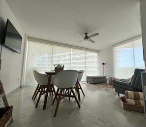 Relax in this spacious living area with a high ceiling, dining table, and comfortable seating.