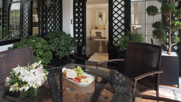 A dining area with wicker furniture, a glass table, and a view of a kitchen through a lattice door. - Terraza de Hamburgo By The Local Way (Mexico City)