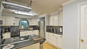 A modern kitchen with white cabinets, a granite countertop, and a stainless steel refrigerator. - Spacious Home w/ Yard, 20 Miles to Olympic NP (Sequim)