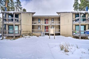 Un edificio a più piani con balconi, una porta rossa e una targa, il tutto immerso nella neve.