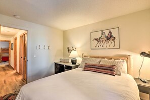 Una camera da letto con un letto grande, una lampada da comodino, un quadro appeso al muro raffigurante cavalli e una testiera in legno.