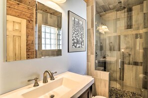 A bathroom with a wooden vanity, a large mirror, a framed picture, and a glass-enclosed shower area. - Tasteful Log Cabin Retreat on Lake Pagosa! (Pagosa Springs)