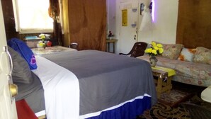 A bedroom with a bed, a sofa, a small table, and a chair. -  Relax N SunShine 
Peaceful, Retreat (May Pen)