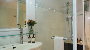 A bathroom with a white sink, a mirror, a glass shower enclosure, and a vase with flowers. - Pasaje de Hamburgo By The Local Way (Mexico City)