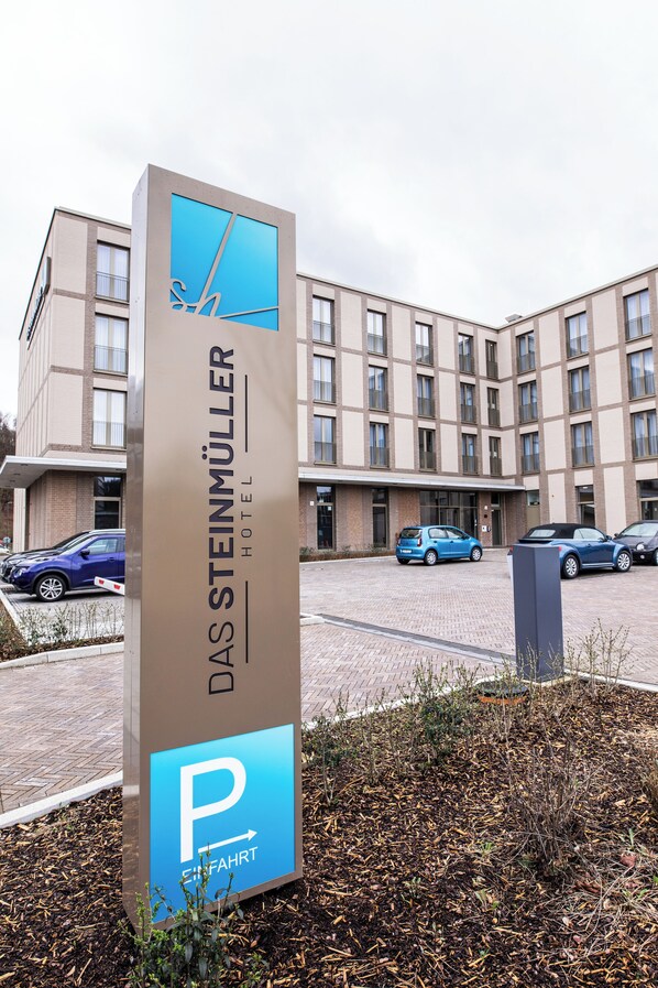 A sign for Das Steinmüller Hotel with a parking sign below it.