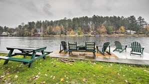 Un espace de pique-nique au bord du lac, avec une table et des chaises, entouré d’arbres et de maisons.