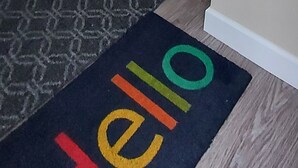Un passadís amb un estora que diu 'Hello' i una catifes amb disseny.