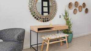 A modern room with a round mirror, wooden desk, bench, and potted plant. - Rockwell 114 (Cape Town)