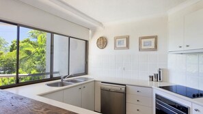 Enjoy a serene view from the large window, with a kitchen equipped for cooking and dining.
