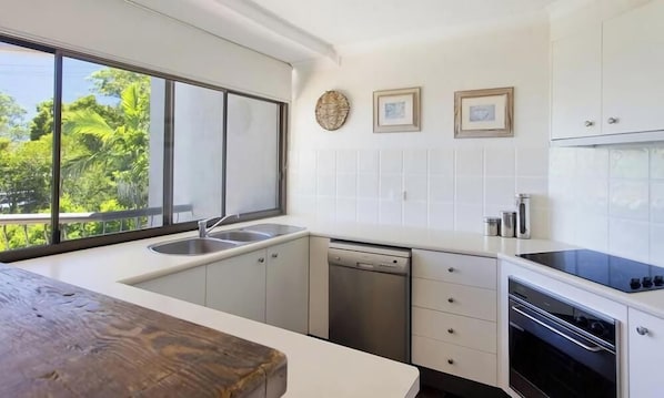 Una cucina moderna con un'ampia finestra, mobili bianchi e forno integrato.