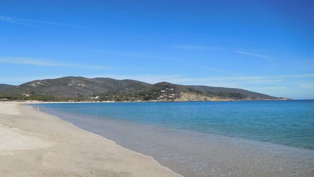 A beach with clear blue water, sandy shore, and a mountain in the background. - Just 300 meters from the sandy beach (Marina di Campo)