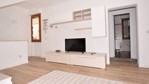 A modern living room with a flat-screen TV, a white entertainment unit, and a herringbone-patterned rug. - Just 300 meters from the sandy beach (Marina di Campo)