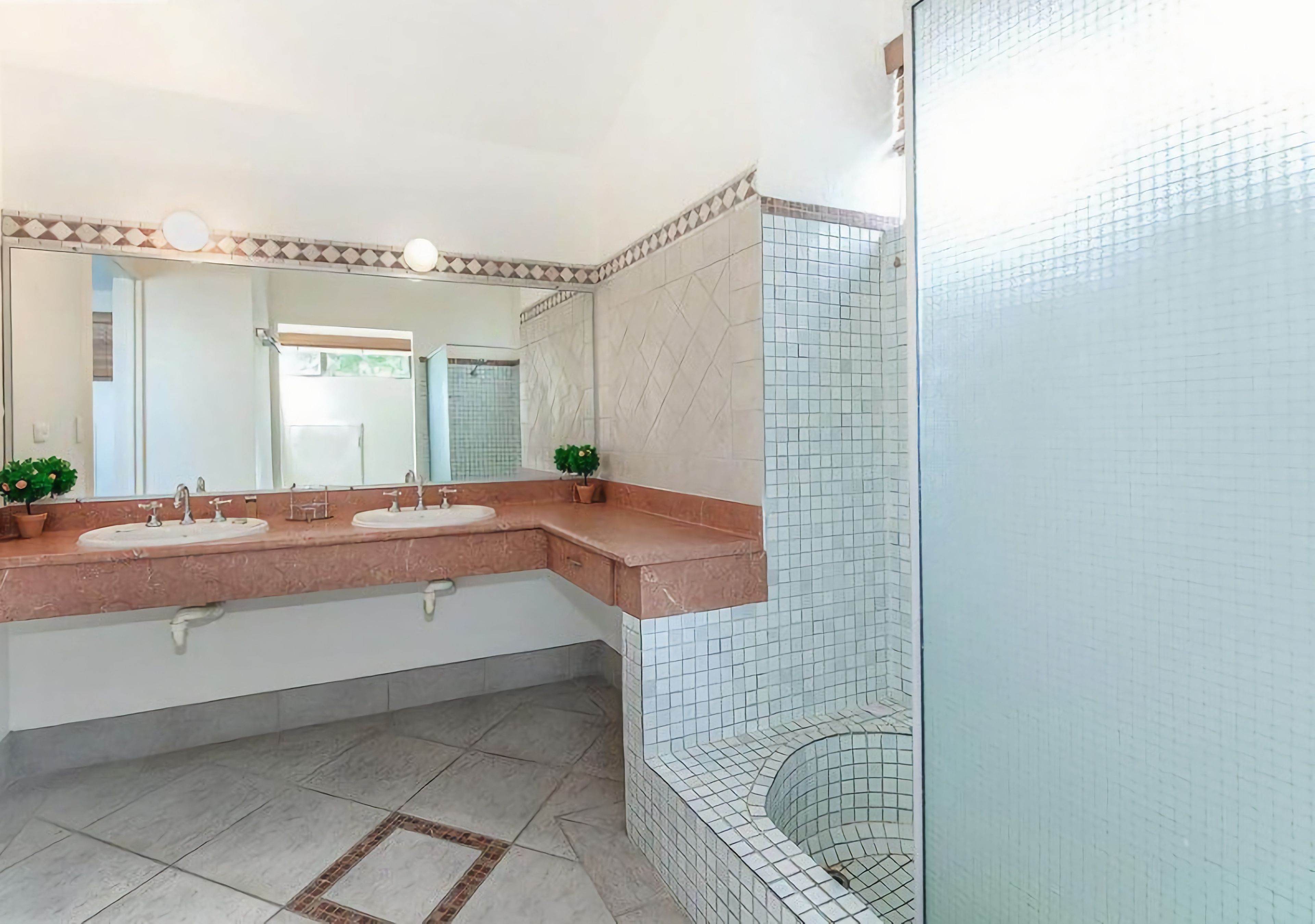 A bathroom with two sinks, a mirror, and a shower area.