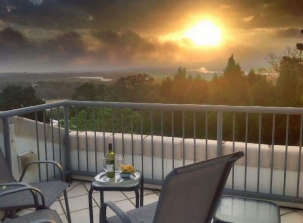 Un balcone con tavolo, sedie e una bottiglia di vino.