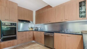 Eine Küche mit Holzausstattung, einem Backofen, einem Geschirrspüler und einer Arbeitsplatte mit Spüle.