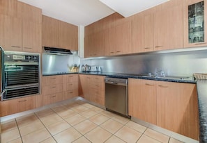 Eine Küche mit Holzausstattung, einem Backofen, einem Geschirrspüler und einer Arbeitsplatte mit Spüle.