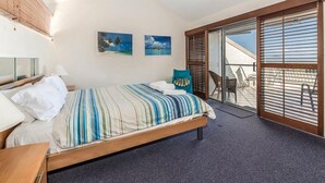 Ein Schlafzimmer mit einem Bett, einem Deckenventilator, einem Fenster mit Jalousien und zwei Wandbildern.
