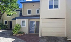 A two-story residential building with a garage, a front door, and a small porch area.