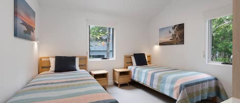 Una camera da letto con due letti singoli, una finestra e opere d'arte alle pareti.