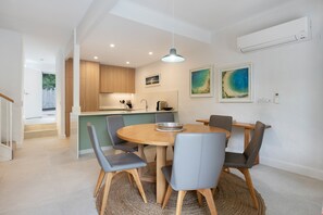 Una cucina moderna con mobili in legno, un'area pranzo con un tavolo rotondo e sedie, e opere d'arte alle pareti.