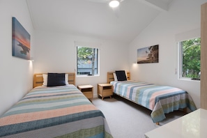 Ein Schlafzimmer mit zwei Betten, Nachttischen und einem Fenster.