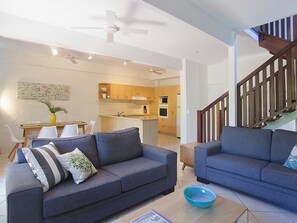 A modern living room with two sofas, a coffee table, and a kitchen in the background.