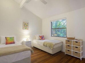 A bedroom with a bed, a bedside table, a lamp, a window with a view, and a storage unit.