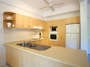 Una cucina moderna con mobili in legno, forno a microonde integrato, forno e frigorifero.