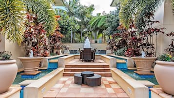 A pool area with a seating arrangement and a fountain.