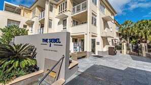 Un hotel de varios pisos con área de recepción, asientos al aire libre y un letrero que indica 'The Sebel Laguna on Hastings'.