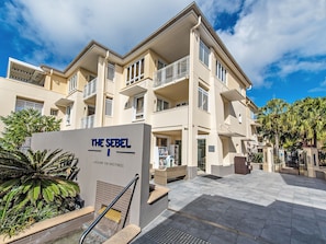 Un hotel de varios pisos con área de recepción, asientos al aire libre y un letrero que indica 'The Sebel Laguna on Hastings'.
