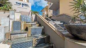 Entrada de un hotel con un cartel que dice 'The Seibel Laguna on Hastings', un juego de escaleras con barandilla metálica y una planta grande en maceta.