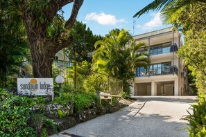 A sign for Sundown Lodge, a building with multiple balconies, and a pathway leading to the entrance. - Sundown Lodge 1 Edgar Bennett Avenue 14 (Noosa Heads)