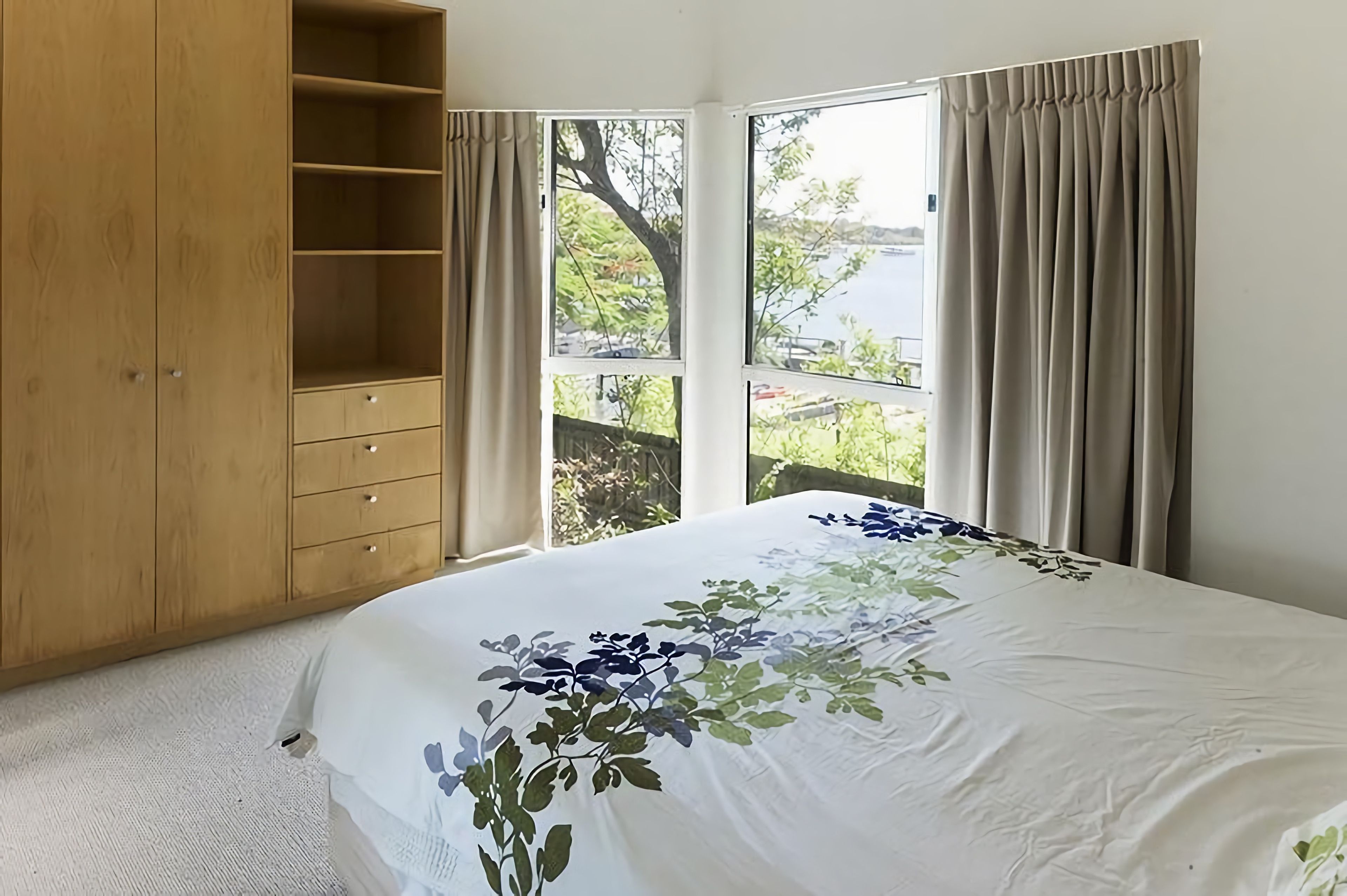 Una camera da letto con un letto grande, un armadio in legno e una finestra con tende.