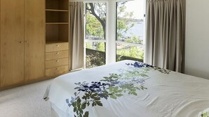 Une chambre avec un grand lit, une armoire en bois et une fenêtre avec des rideaux.