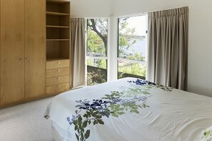 Un dormitorio con una cama grande, un armario de madera y una ventana con cortinas.