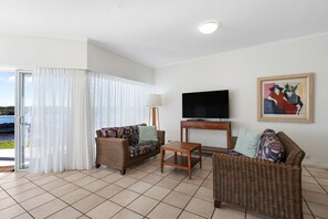 A living room with a sofa, a small table, a television, and a painting on the wall.