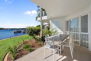 A patio with a table and chairs, overlooking a body of water with boats.