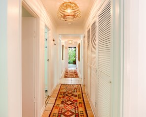 A hallway with a patterned rug, white doors, and a hanging light fixture.