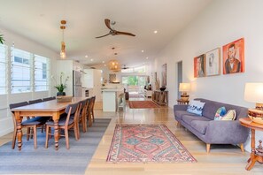 A spacious living area with a dining table, sofa, and artwork on the walls.