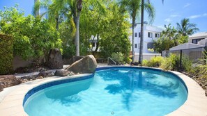pool surrounded by lush tropical plants and large rocks, set amidst a beautifully landscaped area.