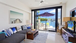 Relax in this stylish living room with a sofa, coffee table, and flat-screen TV, leading to a balcony with a pool view.