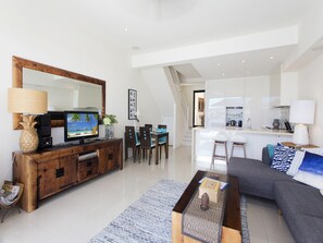 Uma sala de estar moderna com televisão de tela plana, móvel para entretenimento em madeira e um sofá cinza.
