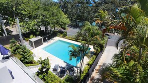 Piscina rodeada de exuberante vegetación y un cielo azul despejado.