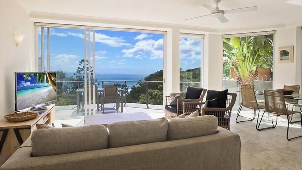 A spacious living area with a large window overlooking a scenic view, a comfortable sofa, and a dining table with chairs.