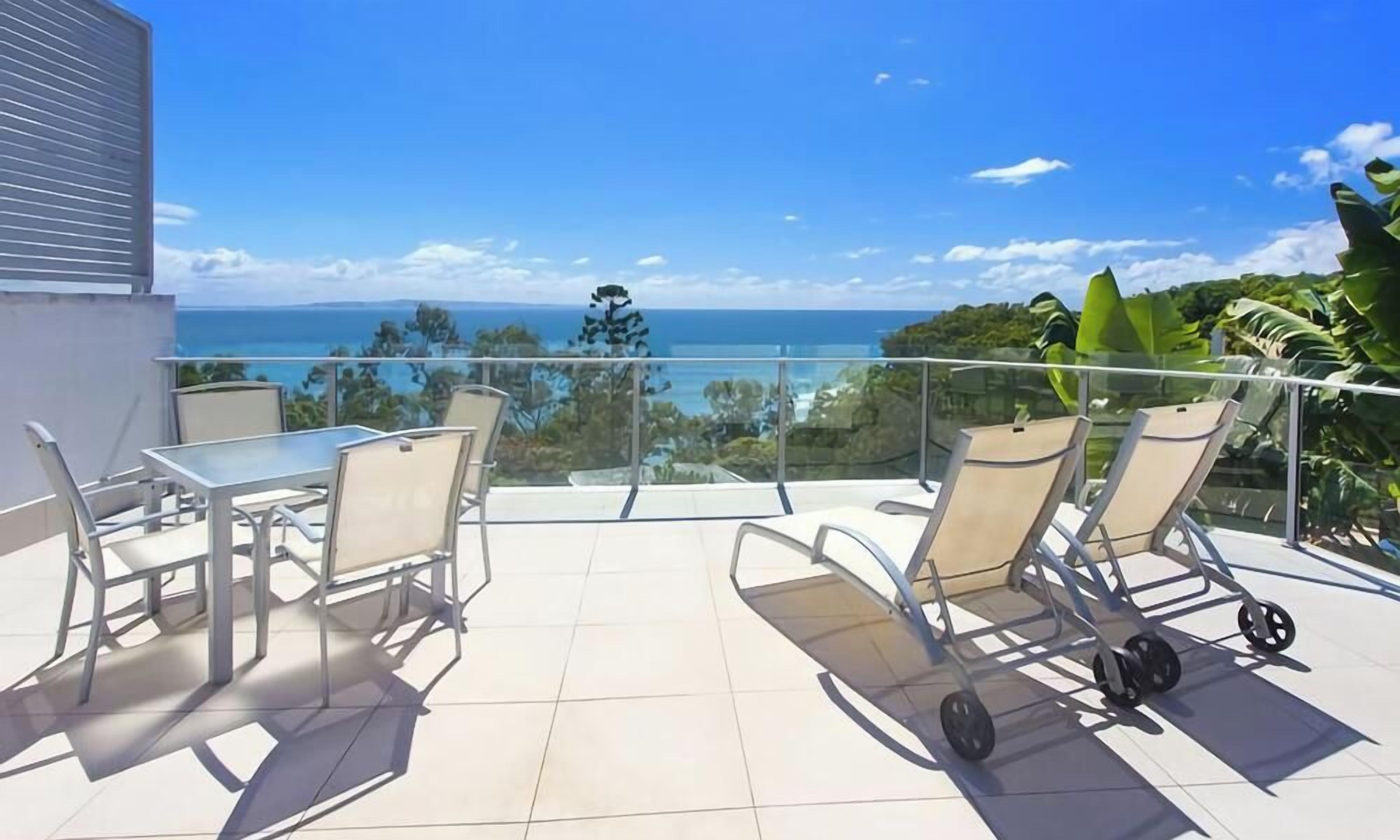 Varanda com mesa e cadeiras, com vista para o oceano.