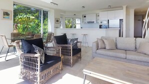A modern living space with wicker furniture, a sofa, and a dining area with a glass table.
