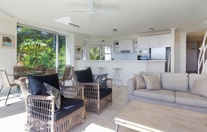 Un espace de vie moderne avec des meubles en osier, un canapé et un coin cuisine.
