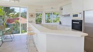 A modern kitchen with a large island, built-in appliances, and large windows.