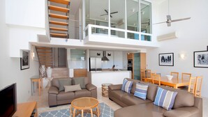 Un appartement moderne comprenant un salon, un coin repas, une cuisine et un escalier menant à l’étage supérieur.